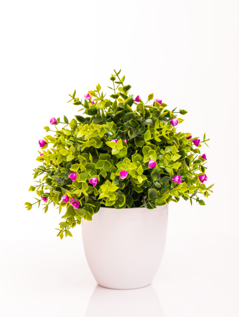 Colourful artificial flowers arranged in a white pot